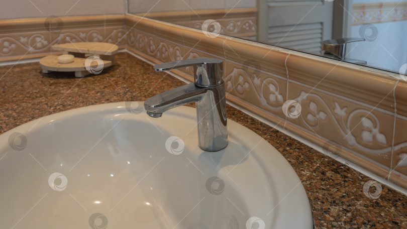 Скачать Металлический смеситель из нержавеющей стали на краю белой керамической раковины для умывания фотосток Ozero