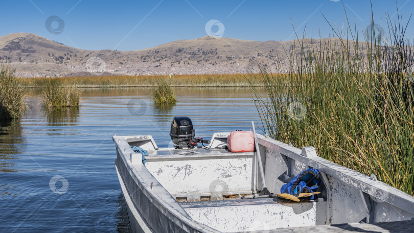 Скачать К берегу озера пришвартована старая, поцарапанная моторная лодка. фотосток Ozero