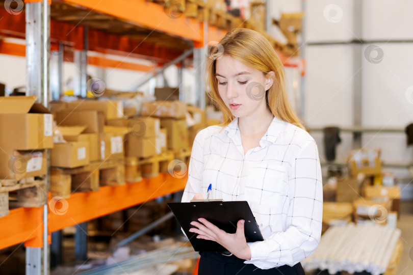 Скачать Женщина-менеджер склада проверяет наличие товара с помощью буфера обмена в логистическом центре фотосток Ozero