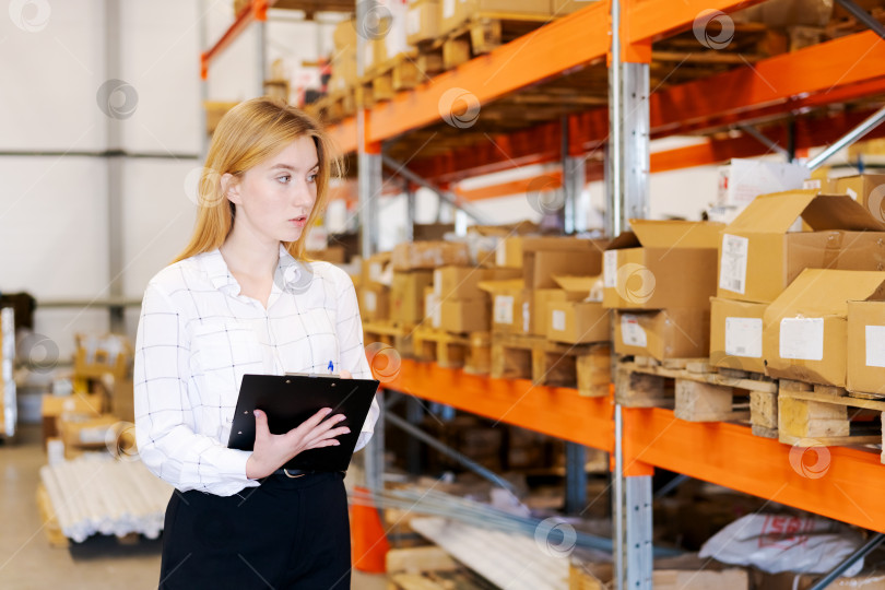 Скачать Молодая женщина-менеджер по логистике с планшетом обмена проверяет запасы на складе фотосток Ozero