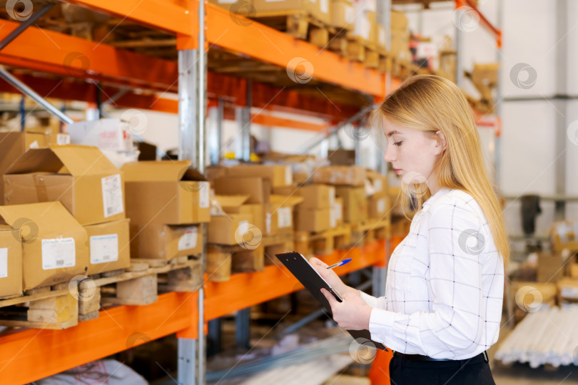 Скачать Молодая женщина-менеджер по логистике с планшетом обмена проверяет запасы на складе фотосток Ozero