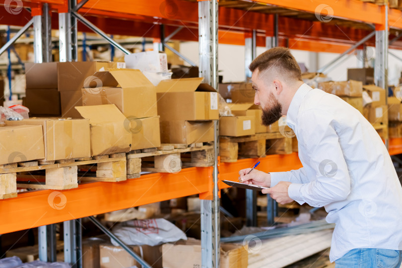 Скачать Менеджер склада проводит инвентаризацию с помощью буфера обмена в складском помещении фотосток Ozero