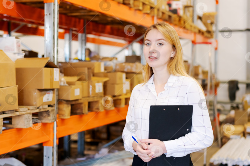 Скачать Улыбающаяся женщина-менеджер склада с планшетом обмена в Распределительном центре фотосток Ozero