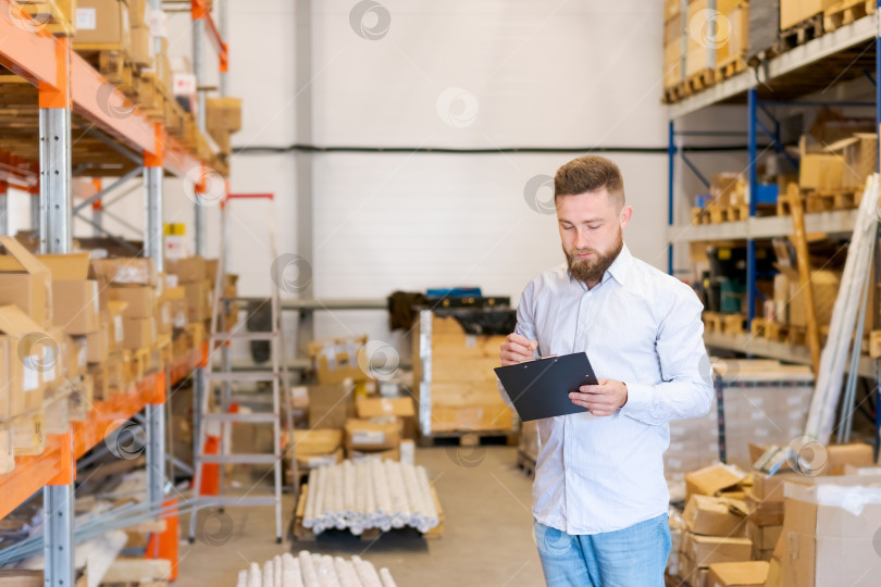 Скачать Начальник склада проверяет запасы с помощью буфера обмена в Крупном распределительном центре фотосток Ozero