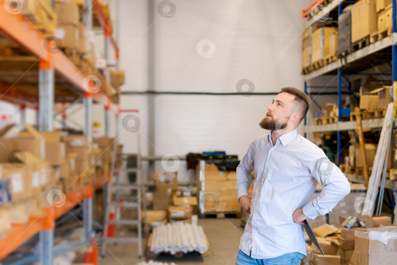 Скачать Начальник склада смотрит на высокие полки во время проверки запасов фотосток Ozero
