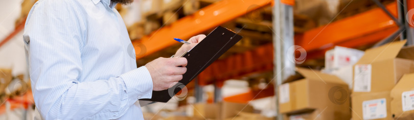 Скачать Крупный план менеджера по логистике, пишущего в буфере обмена на складском складе фотосток Ozero