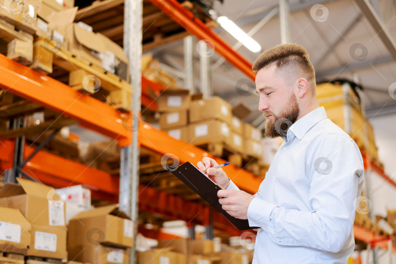 Скачать Сосредоточенный работник склада, регистрирующий запасы с помощью буфера обмена, обеспечивает точность управления запасами фотосток Ozero