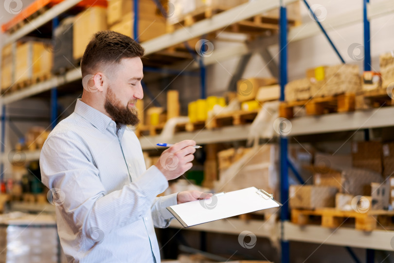 Скачать Улыбчивый менеджер склада просматривает контрольный список, обеспечивает эффективный контроль запасов и логистику фотосток Ozero