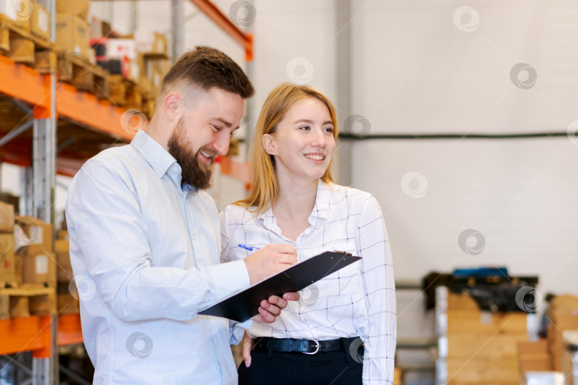 Скачать Улыбчивые менеджеры склада работают вместе с буфером обмена в Распределительном центре фотосток Ozero