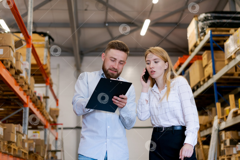 Скачать Контролеры склада проверяют инвентарные записи и разговаривают по смартфону фотосток Ozero