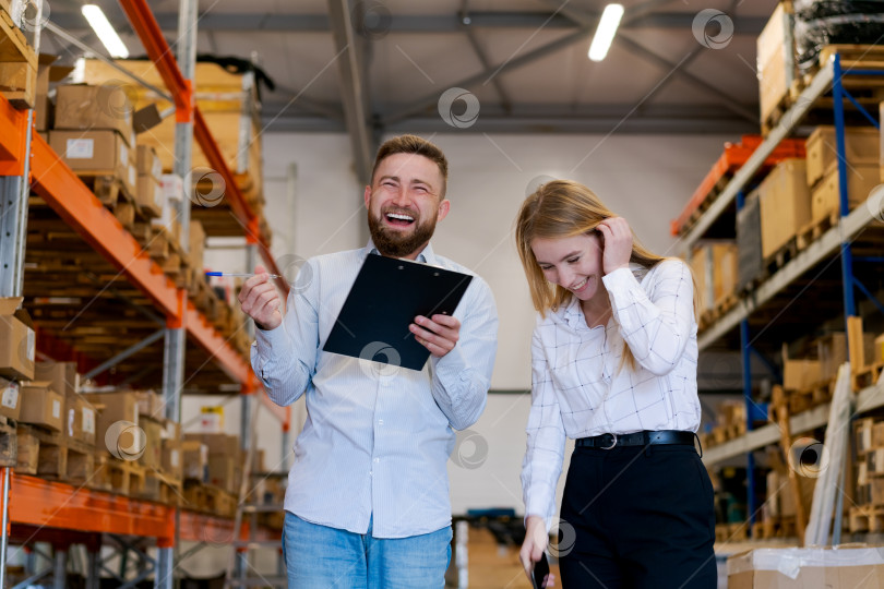 Скачать Счастливые менеджеры по логистике смеются во время проверки запасов на складе фотосток Ozero