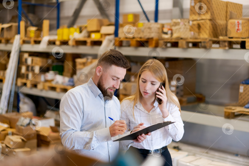 Скачать Менеджеры по логистике проверяют запасы и делают пометки при координации по телефону фотосток Ozero