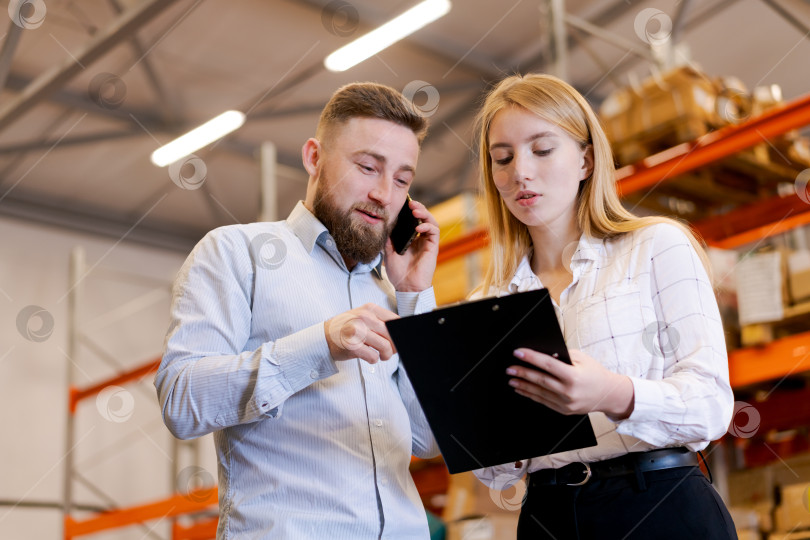 Скачать Менеджеры склада просматривают записи о запасах и координируют свои действия с помощью смартфона фотосток Ozero