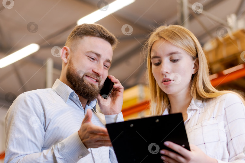 Скачать Крупный план менеджеров склада, обсуждающих аудит запасов с помощью смартфона фотосток Ozero
