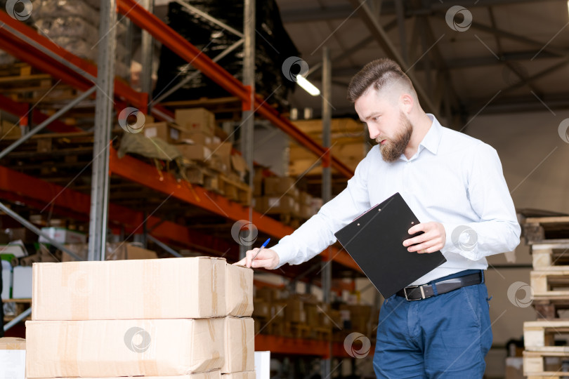 Скачать Инспектор склада проверяет качество груза и маркирует товарные ящики фотосток Ozero