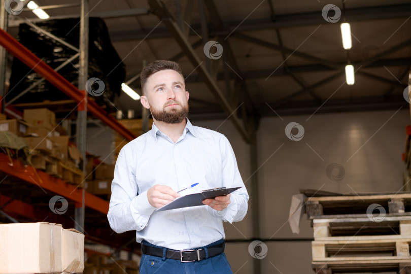 Скачать Заботливый менеджер склада делает пометки в буфере обмена на складе фотосток Ozero