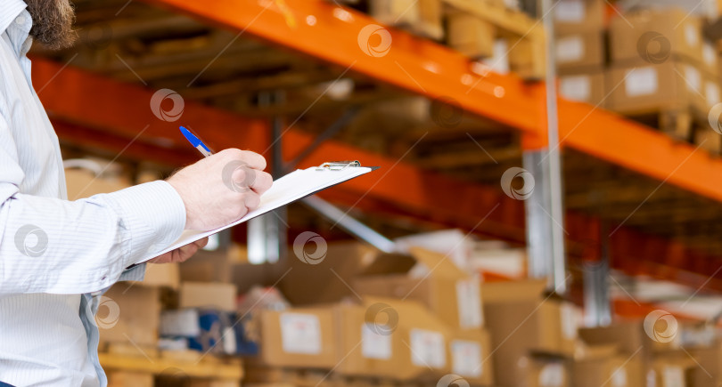 Скачать Крупный план бородатого менеджера склада, пишущего что-то в буфере обмена на складе фотосток Ozero