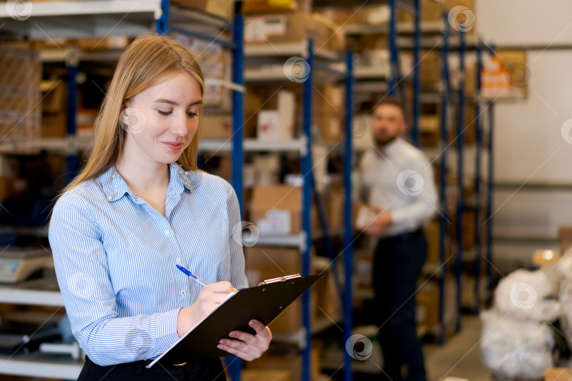 Скачать Улыбающаяся женщина-менеджер по логистике пишет в блокноте обмена на складе фотосток Ozero