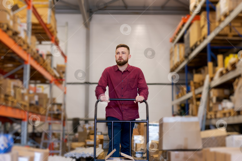 Скачать Работник склада, перевозящий товары на тележке-платформе в Логистическом центре фотосток Ozero