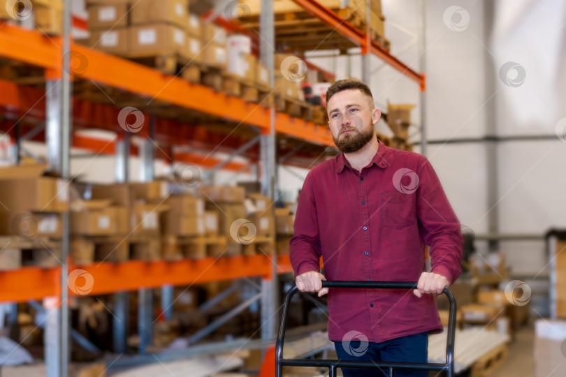 Скачать Целеустремленный логист с ручной тележкой для паллет на большом складе фотосток Ozero