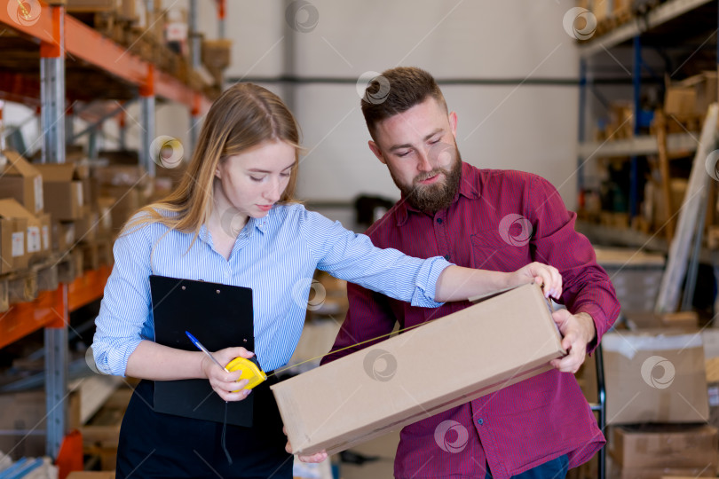Скачать Менеджеры по складской логистике измеряют картонную коробку для отправки фотосток Ozero