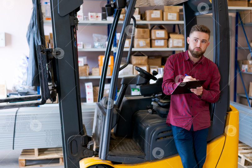 Скачать Менеджер по складской логистике с планшетом обмена, опирающийся на вилочный погрузчик фотосток Ozero