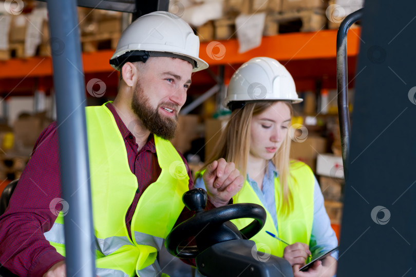 Скачать Команда склада в защитном снаряжении работает вместе с вилочным погрузчиком фотосток Ozero