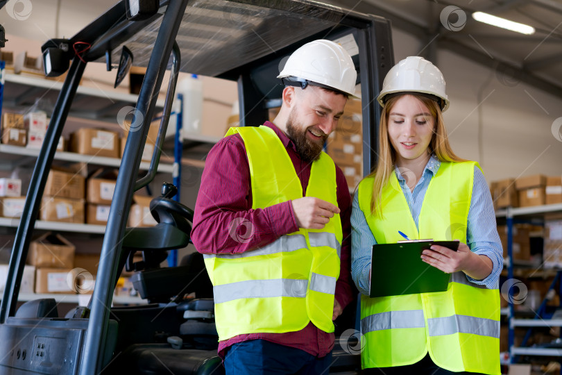 Скачать Успешная Команда Логистов Улыбается Во время Инвентаризации Запасов Возле Вилочного Погрузчика фотосток Ozero