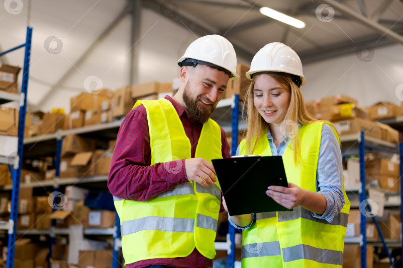 Скачать Два работника склада вместе просматривают контрольный список запасов фотосток Ozero