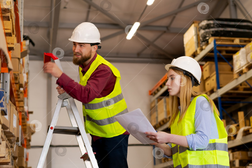 Скачать Счастливая команда склада, работающая над доступом к товарным запасам на высоких полках фотосток Ozero