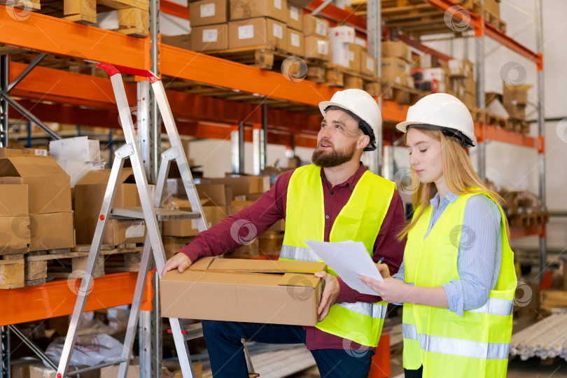 Скачать Работник Склада Определяет местоположение полки, В То время как Коллега Проверяет Инвентарный список фотосток Ozero