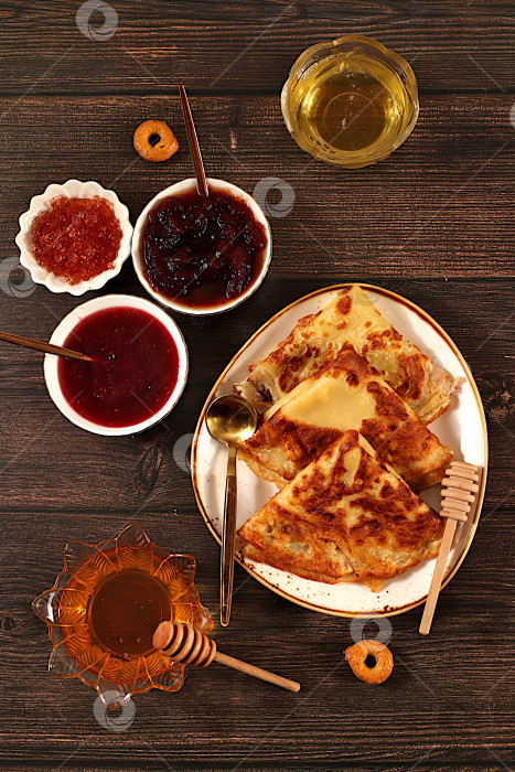 Скачать Вкусные русские блинчики с мягким сыром, медом, вареньем и сметаной на элегантном кухонном столе. Концепция Масленицы и традиционная русская кухня. Рекламный баннер для кафе фотосток Ozero
