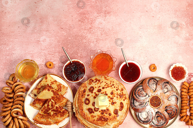 Скачать Вкусные русские блинчики с мягким сыром, медом, джемом, сметаной и рогаликами, солеными крендельками на изысканном праздничном столе.Концепция Масленицы и традиционная русская кухня.Рекламный баннер для кафе фотосток Ozero