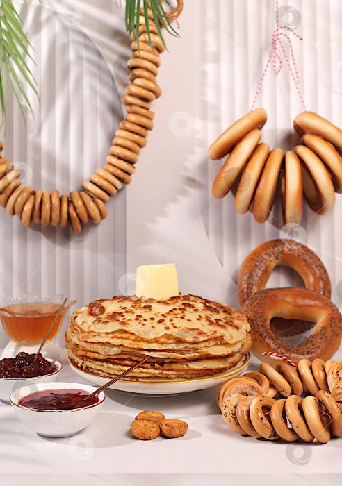 Скачать Вкусные русские блинчики с мягким сыром, медом, джемом, сметаной и рогаликами, солеными крендельками на изысканном праздничном столе.Концепция Масленицы и традиционная русская кухня.Рекламный баннер для кафе фотосток Ozero