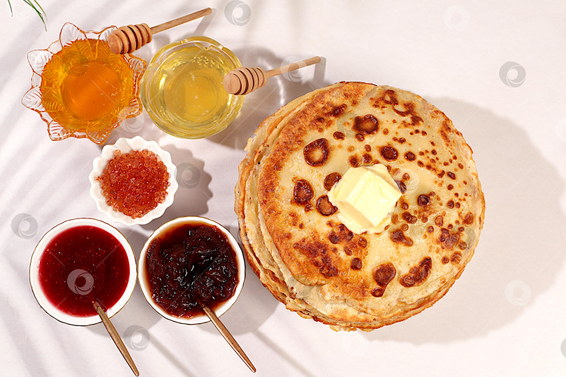 Скачать Вкусные русские блинчики с мягким сыром, медом, вареньем и сметаной на элегантном кухонном столе. Рекламный баннер для кафе или ресторана. Концепция Масленицы и традиционная русская кухня. фотосток Ozero