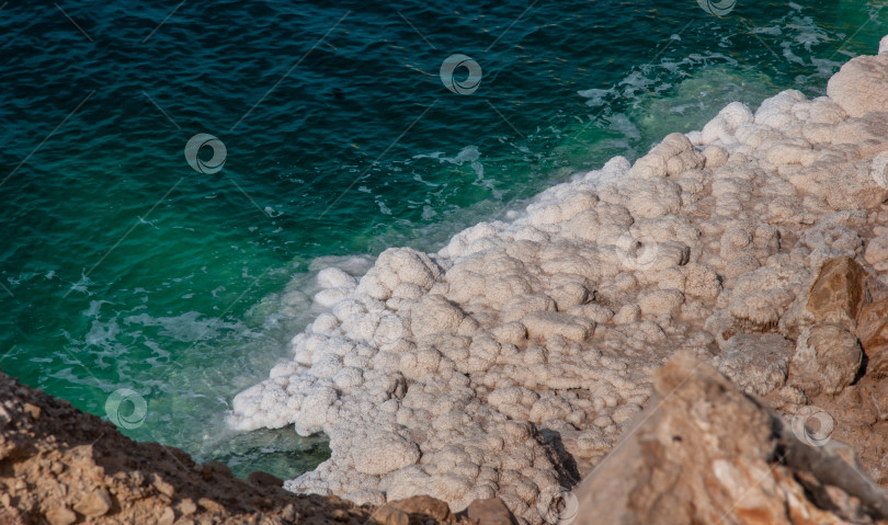 Скачать Побережье Мертвого моря в Иордании. Красивые скалы каскадом спускаются в изумрудную воду Мертвого моря. Кристаллы соли полосами выступают на поверхности воды.  Экологическая тематика фотосток Ozero