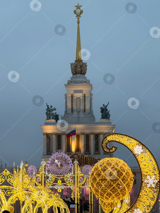 Скачать Москва, Россия - 01.2026: изображение ВДНХ в Москве, украшенное к Новому году. Праздничные огни, световые инсталляции и праздничные украшения создают яркую и праздничную зимнюю атмосферу. Сезонные украшения подчеркивают культовую архитектуру советской эпохи, создавая радостное настроение в преддверии новогодних праздников. фотосток Ozero