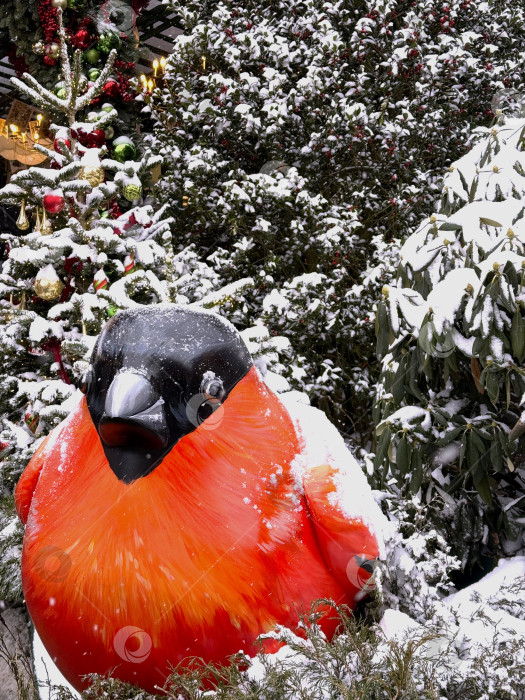 Скачать Праздничное оформление улицы в виде снегиря, покрытого свежим снегом, в окружении подсвеченных рождественских елок в Москве. Уютная зимняя атмосфера с сезонными огнями, праздничным настроением и элементами декора, характерными для празднования Нового года в городе. фотосток Ozero