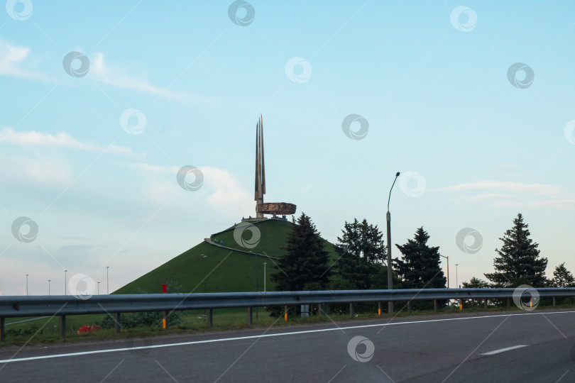 Скачать Беларусь, Минск - 19/07/2025: По шоссе проходит статуя, возвышающаяся на вершине холма фотосток Ozero