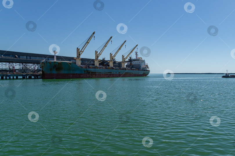 Скачать Большой морской корабль голубого цвета, сухогруз или балкер возле балкерного терминала в изумрудных водах Черного моря. Солнечный день фотосток Ozero