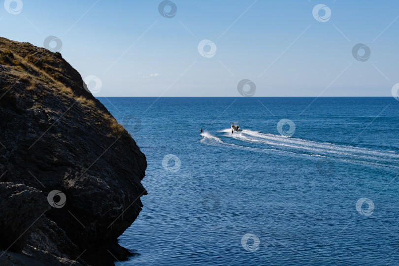 Скачать Активный отдых на Черном море. Два человека рассекают волны на водных лыжах за катером. Судакская бухта, Крым. фотосток Ozero