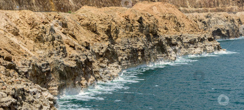 Скачать Побережье Мертвого моря в Иордании. Красивые скалы каскадом спускаются в изумрудную воду Мертвого моря. Кристаллы соли полосками показывают уровень уходящей воды в 2011 году.  Экологическая тема. Есть место для вашего текста фотосток Ozero