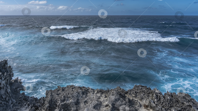 Скачать Бескрайний голубой океан. Волны пенятся, разбиваясь о скалистый берег фотосток Ozero