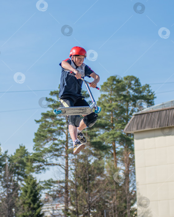 Скачать Россия, Красноярск 02 мая 2025г. Подросток на трюковом самокате в скейт-парке выполняет трюк во время прыжка. фотосток Ozero