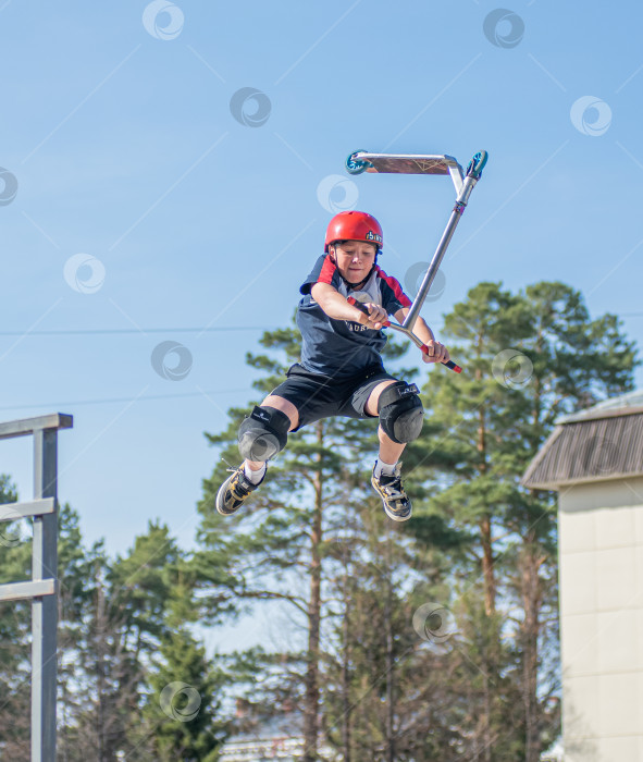 Скачать Россия, Красноярск 02 мая 2025г. Подросток на трюковом самокате в скейт-парке выполняет трюк во время прыжка. фотосток Ozero