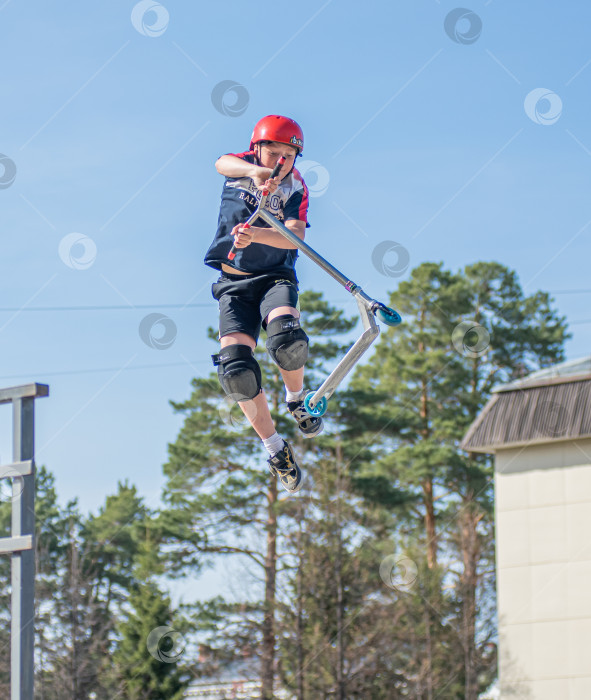 Скачать Россия, Красноярск 02 мая 2025г. Подросток на трюковом самокате в скейт-парке выполняет трюк во время прыжка. фотосток Ozero