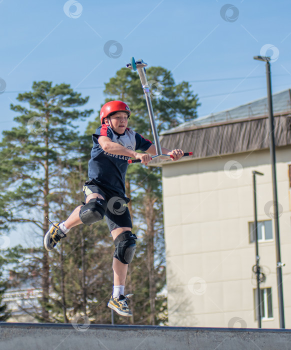 Скачать Россия, Красноярск 02 мая 2025г. Подросток на трюковом самокате в скейт-парке выполняет трюк во время прыжка. фотосток Ozero
