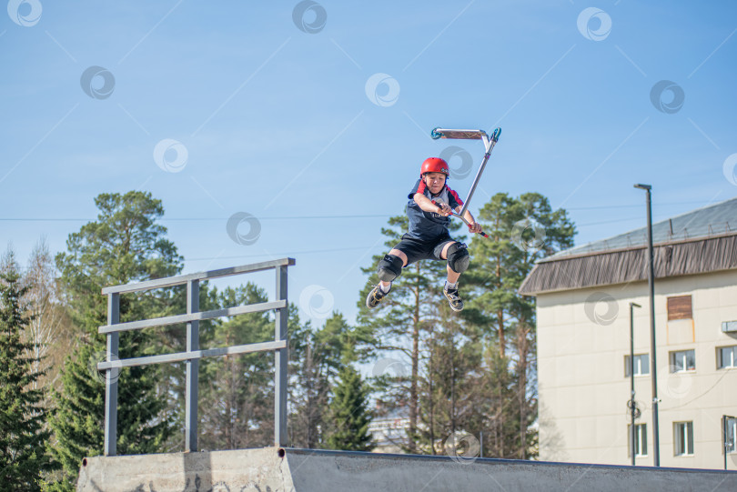 Скачать Россия, Красноярск 02 мая 2025г. Подросток на трюковом самокате в скейт-парке выполняет трюк во время прыжка. фотосток Ozero