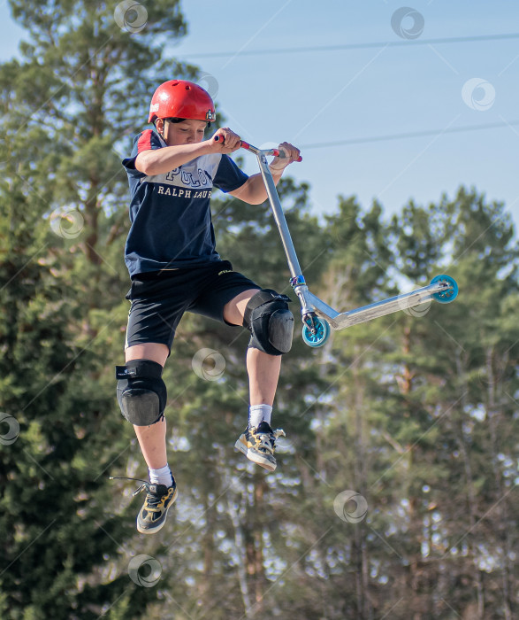 Скачать Россия, Красноярск 02 мая 2025г. Подросток на трюковом самокате в скейт-парке выполняет трюк во время прыжка. фотосток Ozero