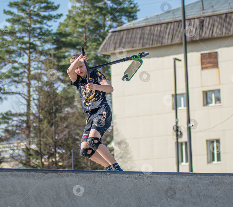 Скачать Россия, Красноярск 02 мая 2025г. Подросток на трюковом самокате в скейт-парке выполняет трюк во время прыжка. фотосток Ozero